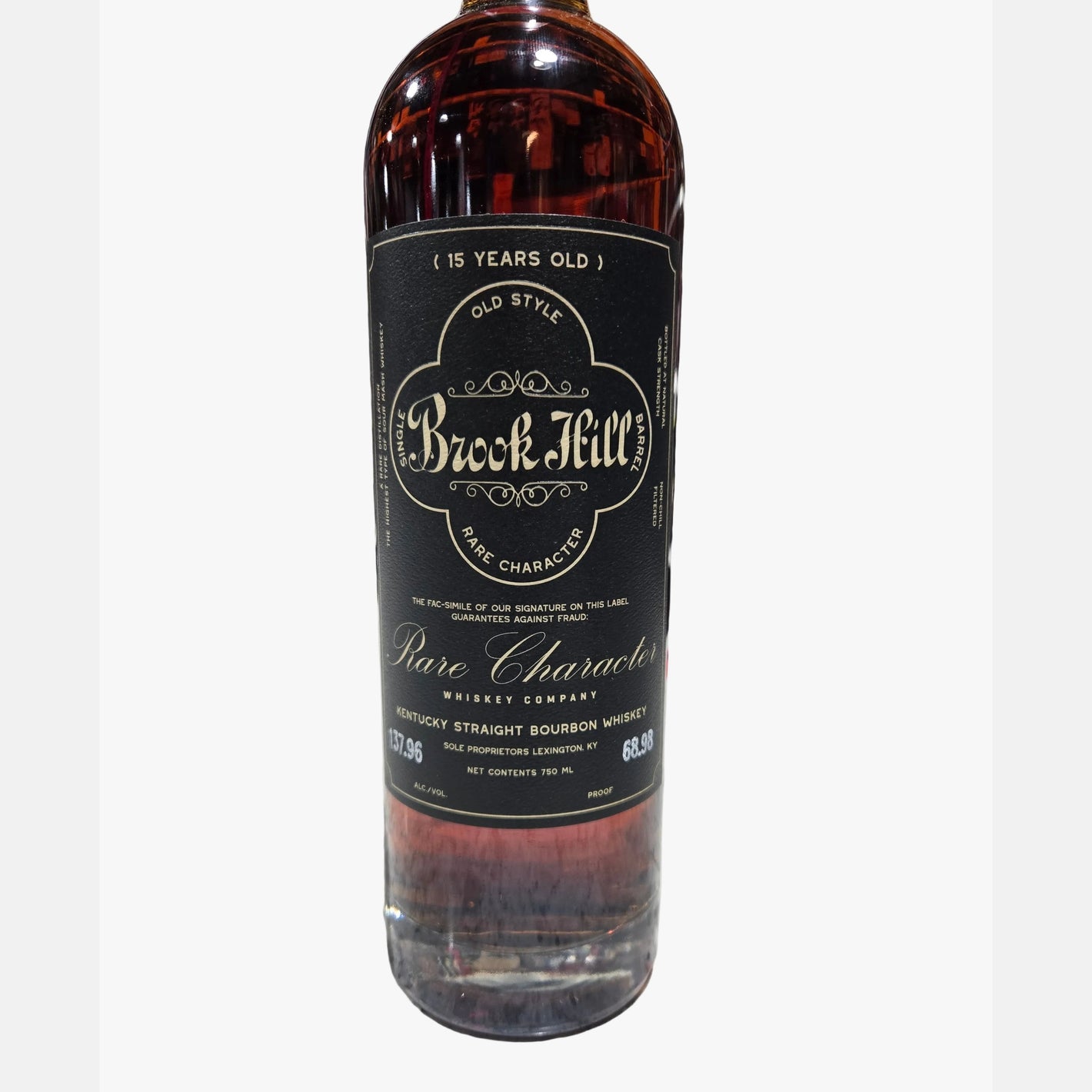A bottle of Brock Mill Pure Character 15 Years Old bourbon whiskey standing on a speckled countertop with a blurred liquor store shelf in the background.