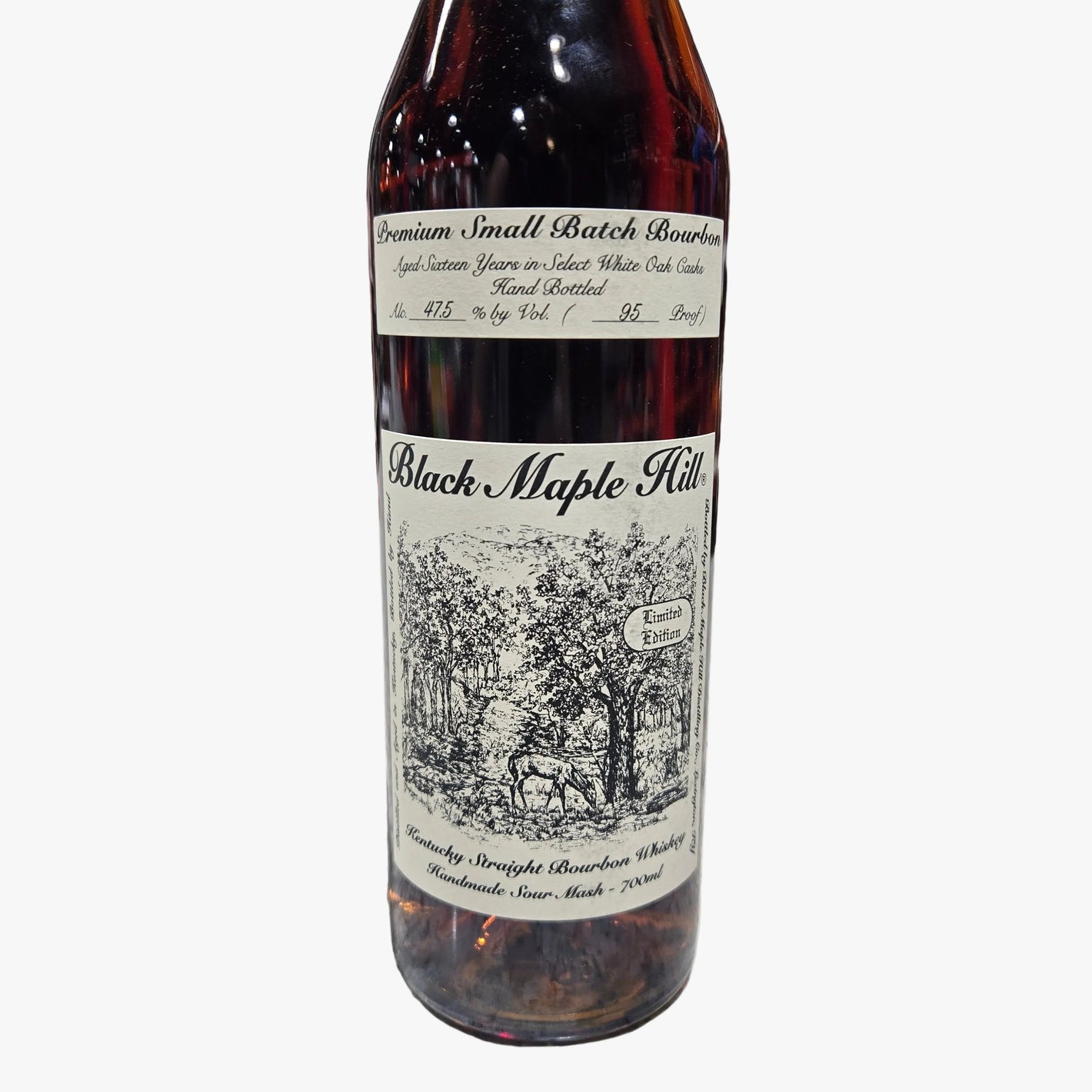 A bottle of Black Maple Hill bourbon whiskey on a speckled stone countertop in a liquor store, with a blurred background of shelves and bottles.
