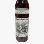 A bottle of Black Maple Hill bourbon whiskey on a speckled stone countertop in a liquor store, with a blurred background of shelves and bottles.