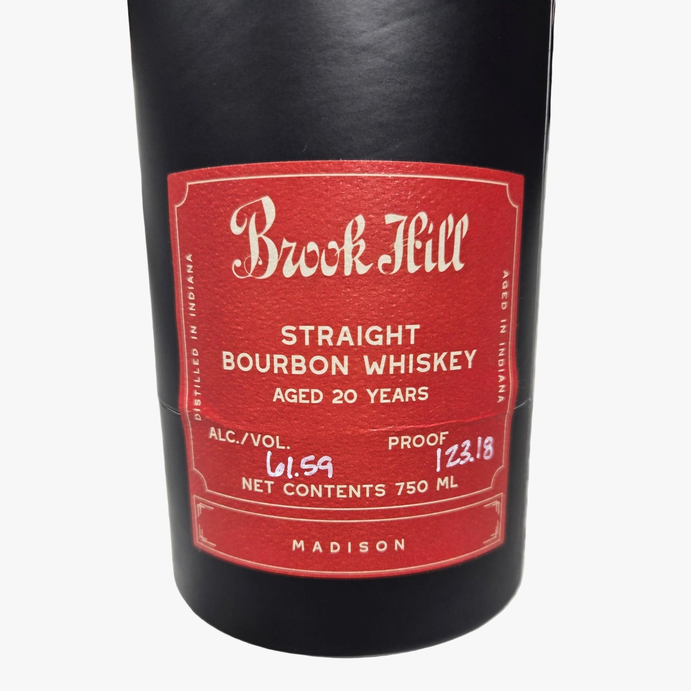 A close-up of a Buck Feill Straight Bourbon Whiskey bottle, showing the black glass body and a red label with white text, resting on a gray marble surface.