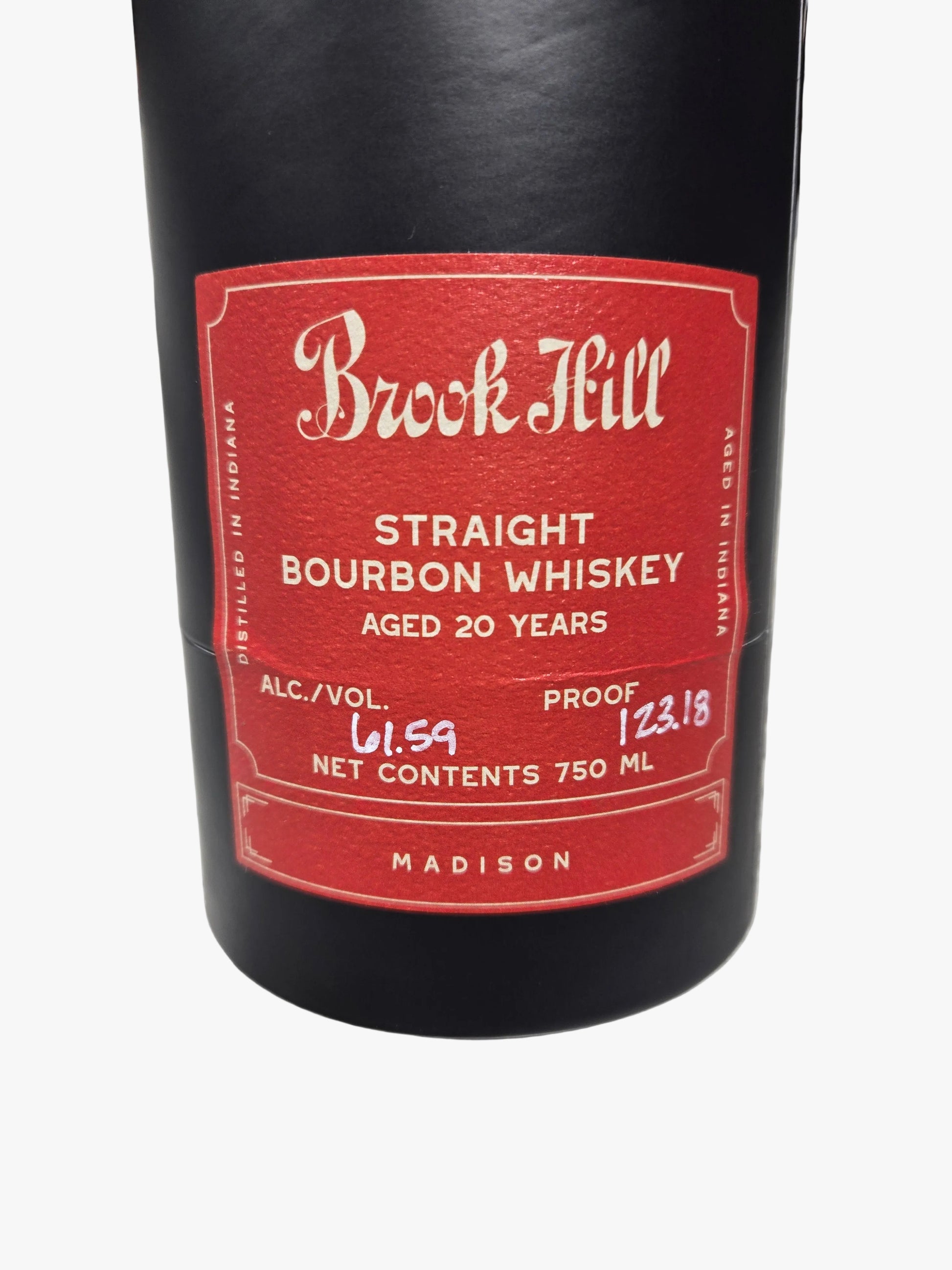A close-up of a Buck Feill Straight Bourbon Whiskey bottle, showing the black glass body and a red label with white text, resting on a gray marble surface.