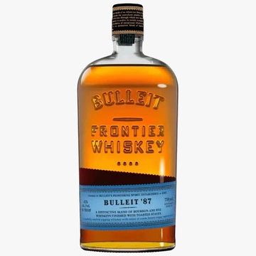 A bottle of Bulleit Frontier Whiskey '87, showing the amber-brown whiskey inside a clear glass bottle with a black and gold cap and a light blue label.