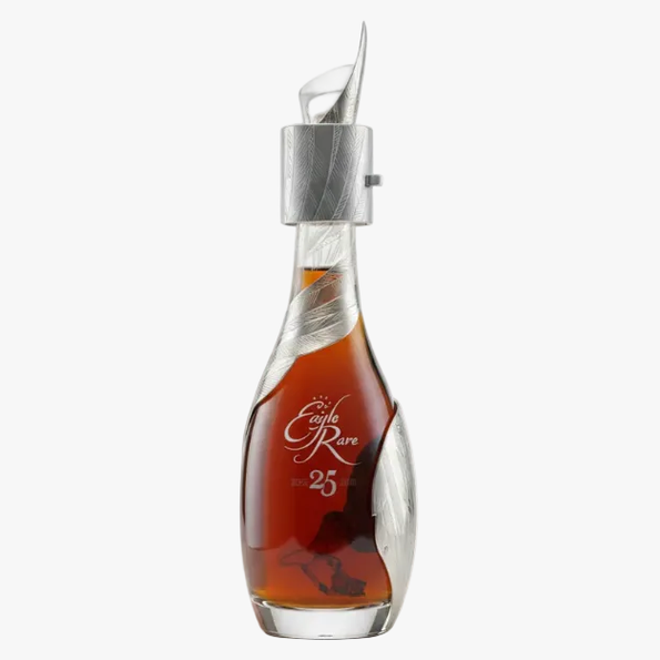 A luxury bottle of cognac with a sculptural clear glass body, etched silver details, and a silver pour spout. The amber liquid inside is labeled 'An Eagle Rare 25 Anvil Edition'.