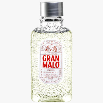 A bottle of Gran Malo Spic Tamarindo liquor, featuring a clear, textured glass body showing the pale yellow liquid inside, a white label with bold red lettering, and a silver metallic cap, set against a plain white background.