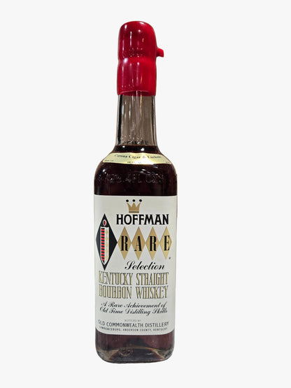 A bottle of Hoffman Rare Kentucky Straight Bourbon Whiskey stands in front of its open cardboard box on a marble countertop, with a blurred liquor store shelf background.