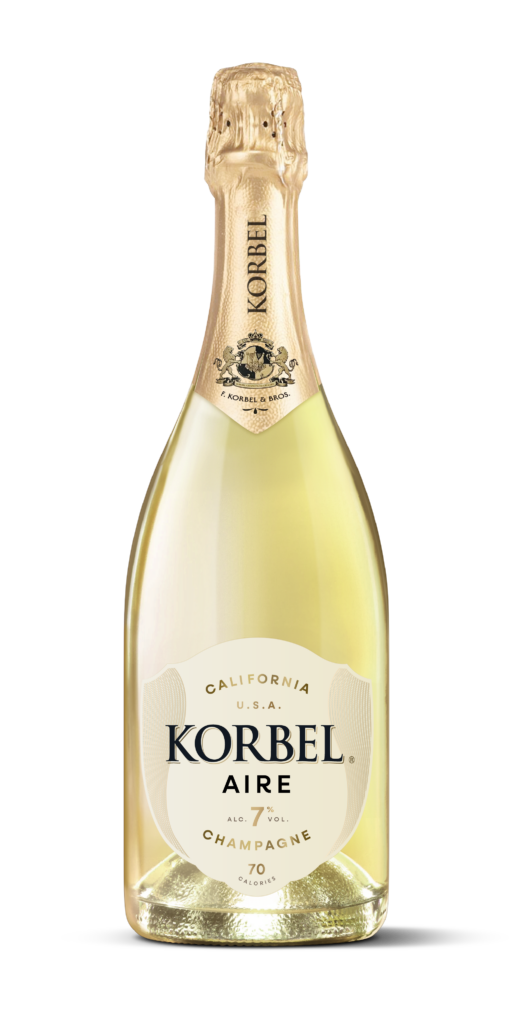 A bottle of Korbel Aire Champagne with pale golden liquid, a cream-colored label, and a gold foil neck wrap, isolated on a white background.