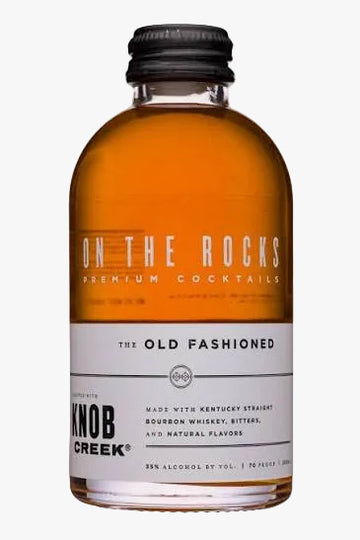 A bottle of Knob Creek On the Rocks Premium Cocktails, 'The Old Fashioned' flavor, featuring amber whiskey in a clear glass bottle with a black cap and a white label.