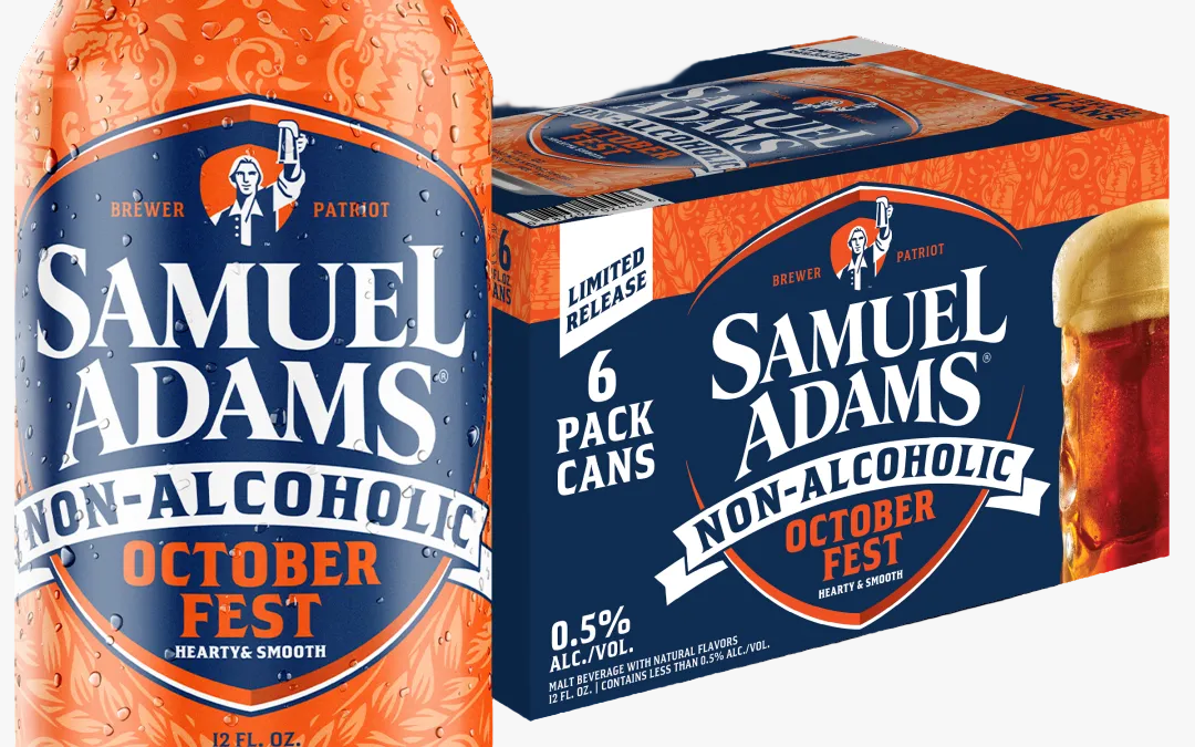 A bottle and a 6-pack box of Samuel Adams Non-Alcoholic October Fest beer on a plain white background. The packaging is predominantly dark blue and orange, with white text and a small illustration of a figure holding a flag.