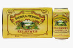 A yellow carton and matching can of Sierra Nevada Kellerweis Heifeweizen beer displayed on a wooden table with a blurred garden background.