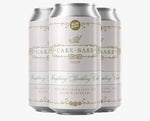 Three silver aluminum beverage cans with white labels and gold decorative text, shown on a pale pink background. The center can reads 'The Cake Bake Shop' and 'Raspberry Sparkling Cider,' with smaller text indicating a collaboration at the top and 'AVAILABLE FEB.